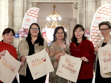 Die fünf Frauen stehen im Wiener Rathaus und halten jeweils eine Stofftasche mit Sprüchen zum Frauentag in Händen.