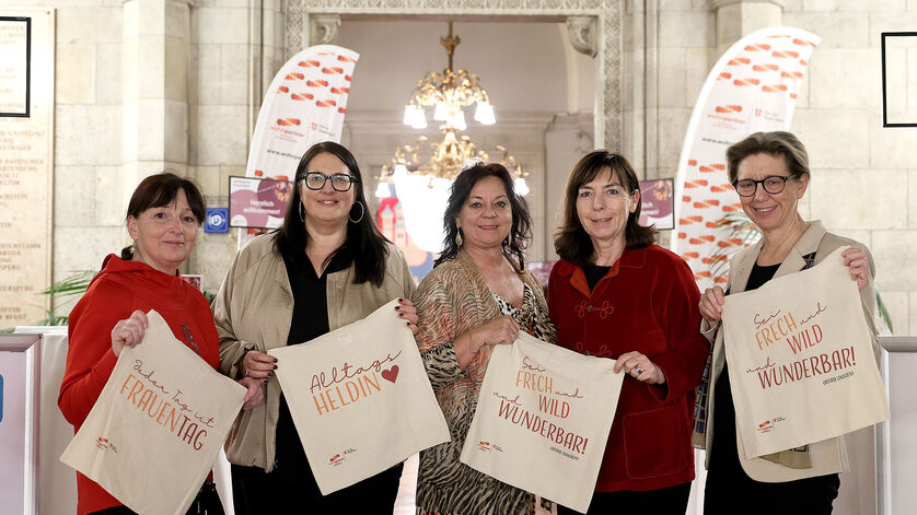 Die fünf Frauen stehen im Wiener Rathaus und halten jeweils eine Stofftasche mit Sprüchen zum Frauentag in Händen.