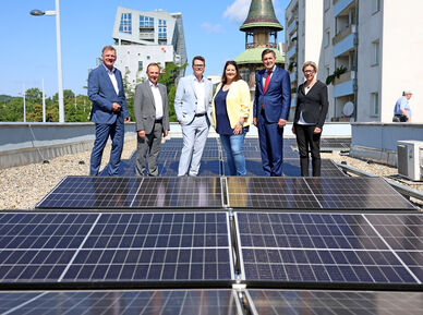 Michael Strebl (Wien Energie), Gerald Bischof (Bezirksvorsteher), Jürgen Czernohorszky (Klimastadtrat), Kathrin Gaál (Vizebürgermeisterin & Wohnbaustadträtin), Peter Hanke (Wirtschaftsstadtrat) und Karin Ramser (Wiener Wohnen) besichtigen die neue PV-Anlage am Gemeindebau in Liesing.