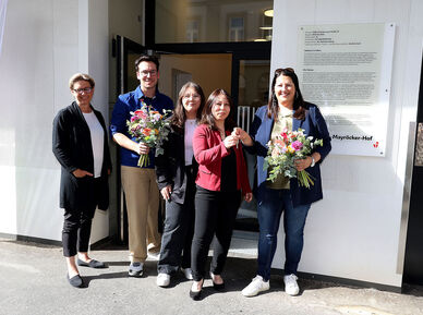 Wiener Wohnen Direktorin Karin Ramser, Bezirksvorsteher Michael Luxenberger und Vizebürgermeisterin und Wohnbaustadträtin Kathrin Gaál mit frisch eingezogenen Bewohnerinnen stehen vor dem Eingang des Gemeindebau NEU in der Schönbrunnerstraße. Kathrin Gaál überreicht der neuen Mieterin symbolisch ihren Wohnungsschlüssel. Sie hält dabei auch einen bunten Blumenstrauß in der Hand, ebenso wie der Bezirksvorsteher von Margareten