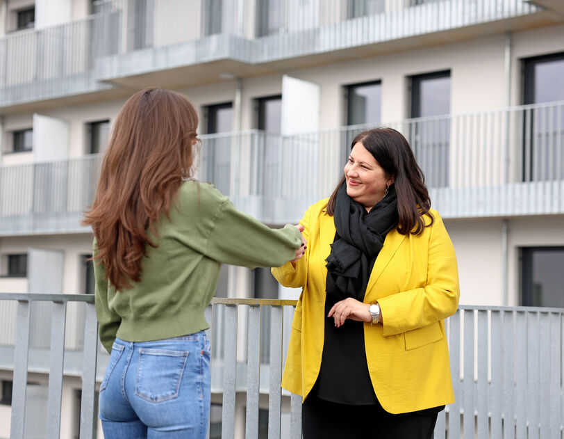 Kathrin Gaál steht einer langhaarigen jungen Frau gegenüber. Die Vizebürgermeisterin schüttelt der Frau die Hand.